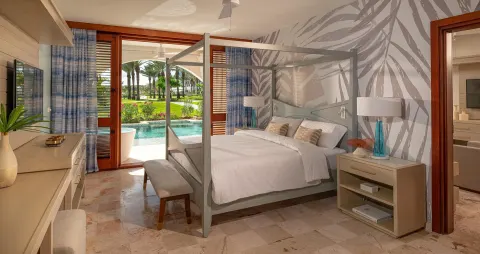 Four-poster king bedroom opening to a swim-up pool at Sandals Royal Curacao.
