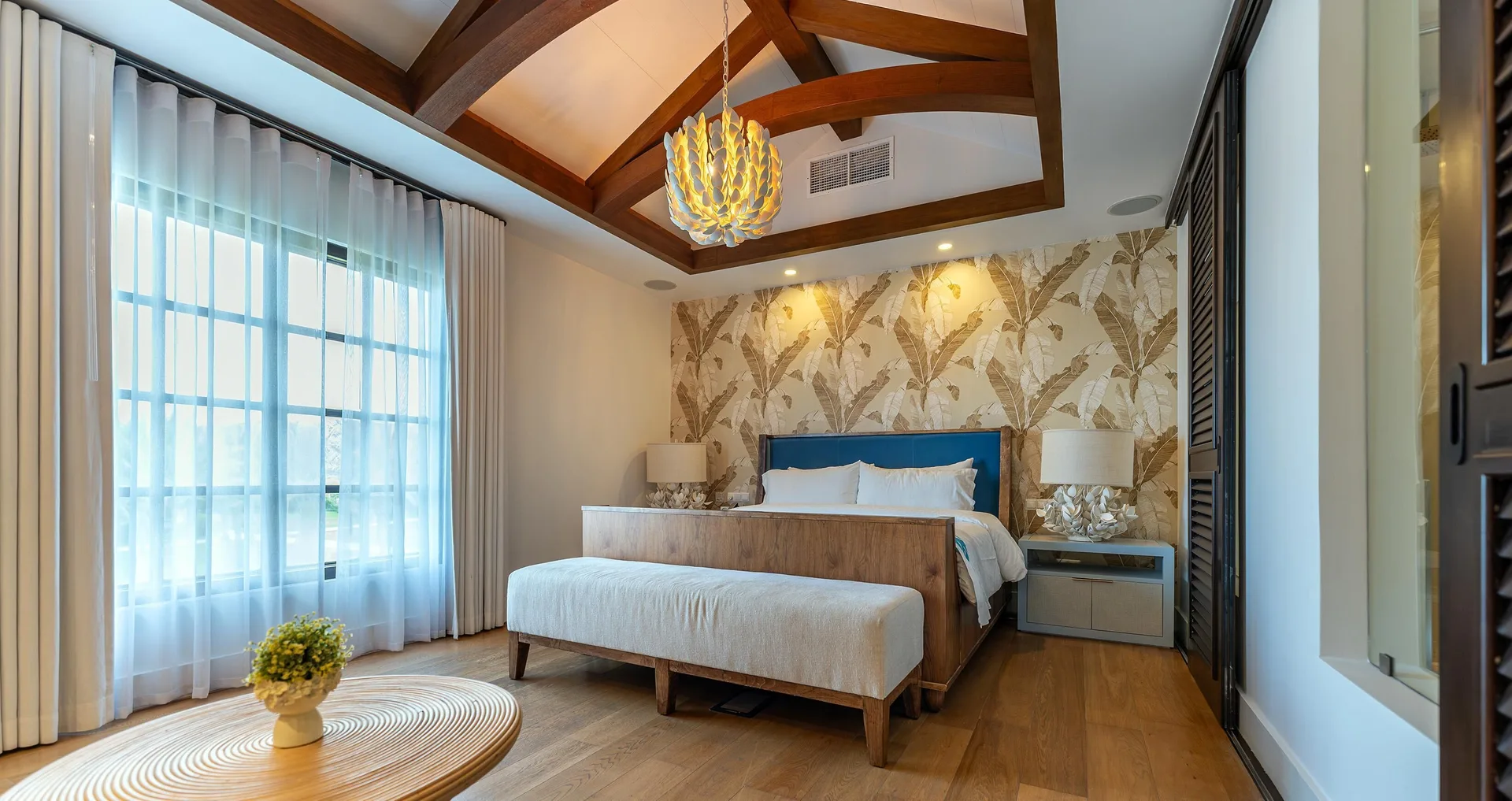 King bedroom with vaulted beams and tropical wallpaper at Sandals Royal Curacao.