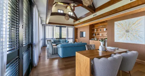 High-ceiling living and dining room with blue sofas at Sandals Royal Curacao.