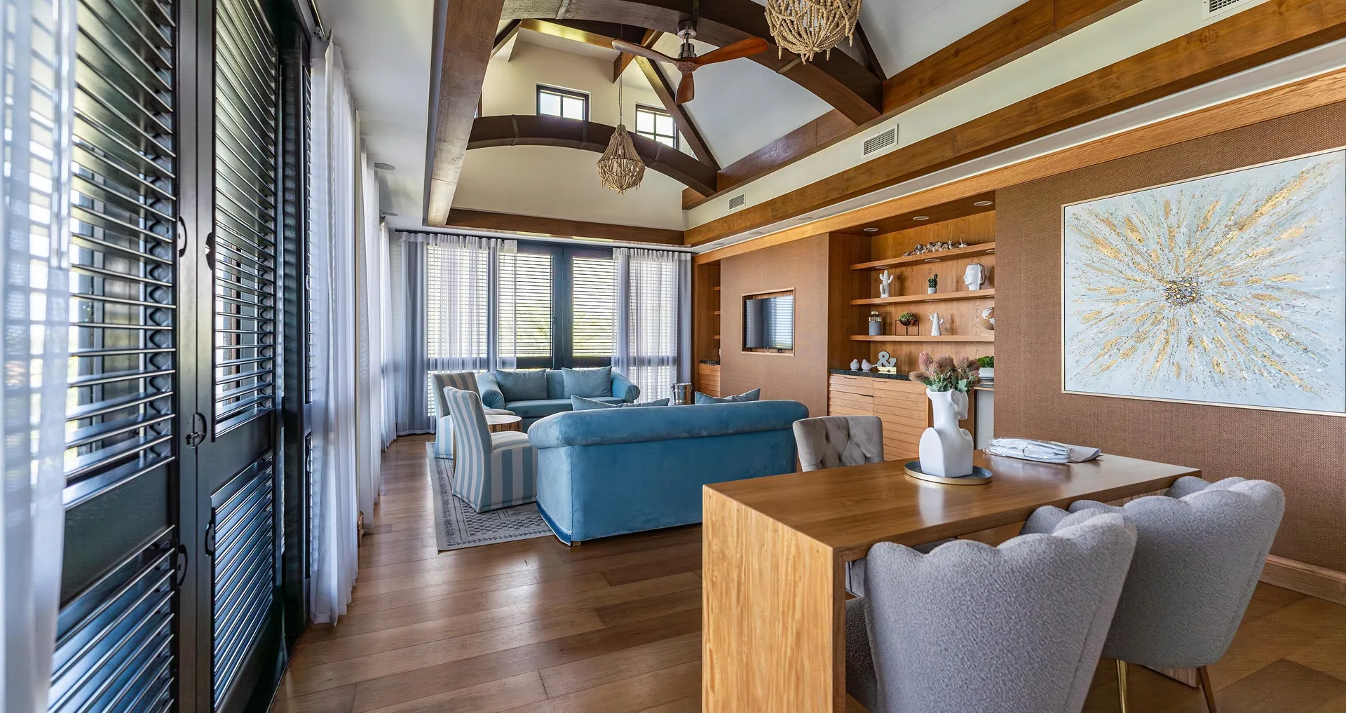High-ceiling living and dining room with blue sofas at Sandals Royal Curacao.