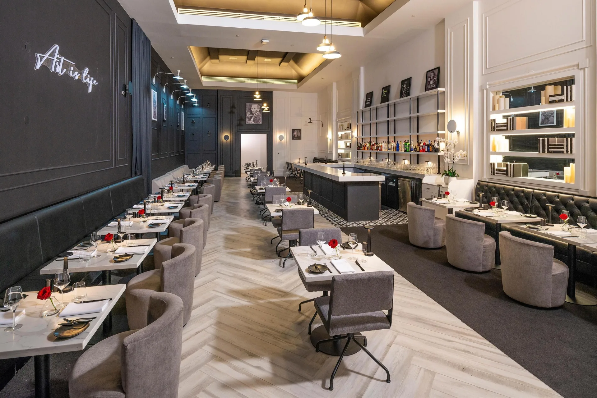 Elegant dark-toned dining room with bar and set tables at Sandals Royal Curacao.