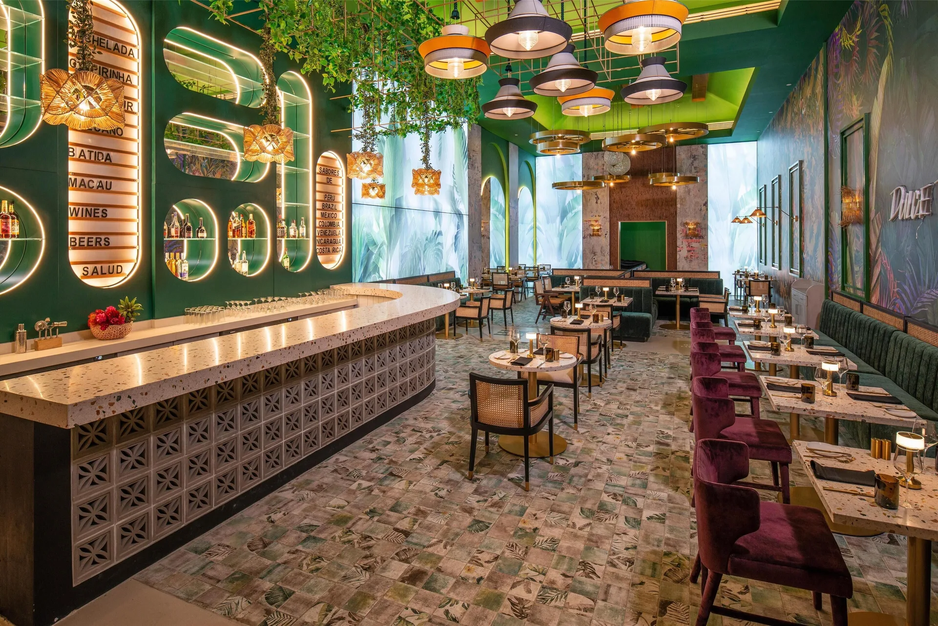 Tropical bar and dining room with green walls and pendant lights at Sandals Royal Curacao.
