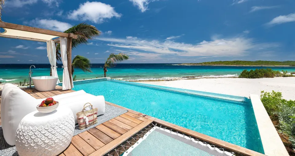 Private pool terrace with outdoor tub and sea view at an Awa Bungalow at Sandals Royal Curacao.