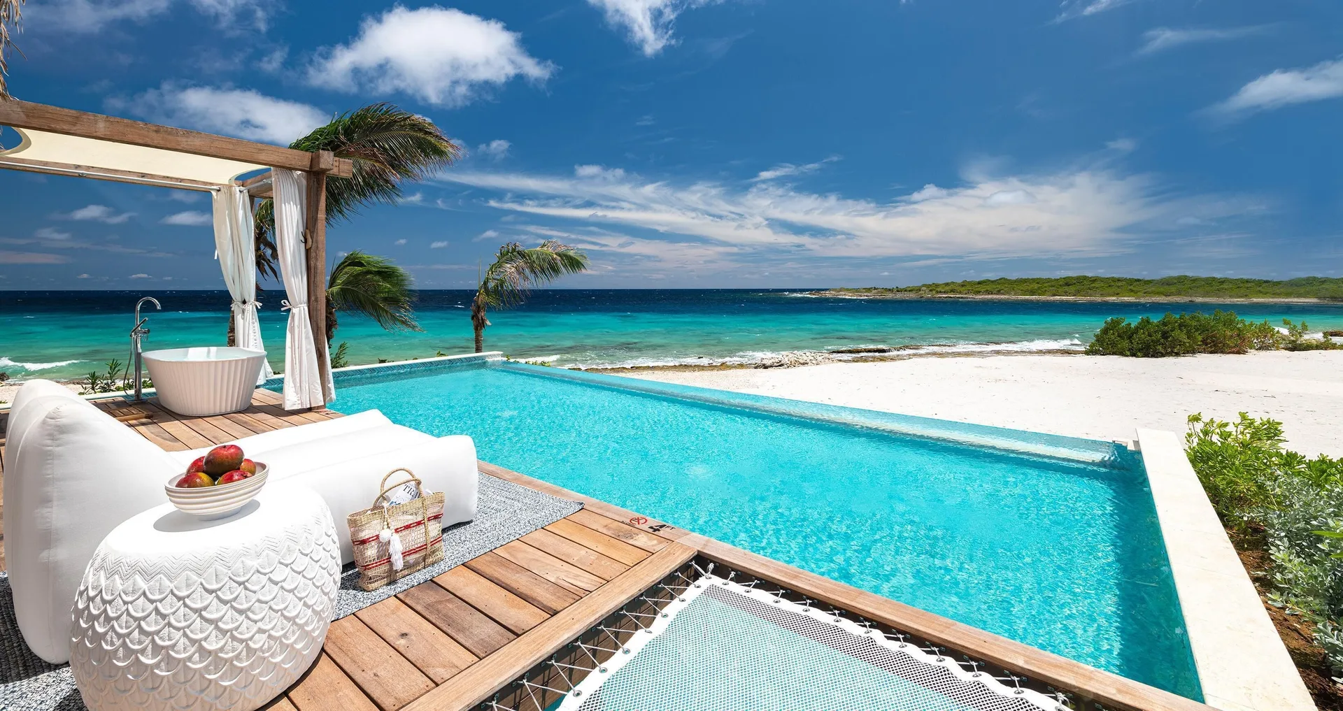 Private pool terrace with outdoor tub and sea view at an Awa Bungalow at Sandals Royal Curacao.