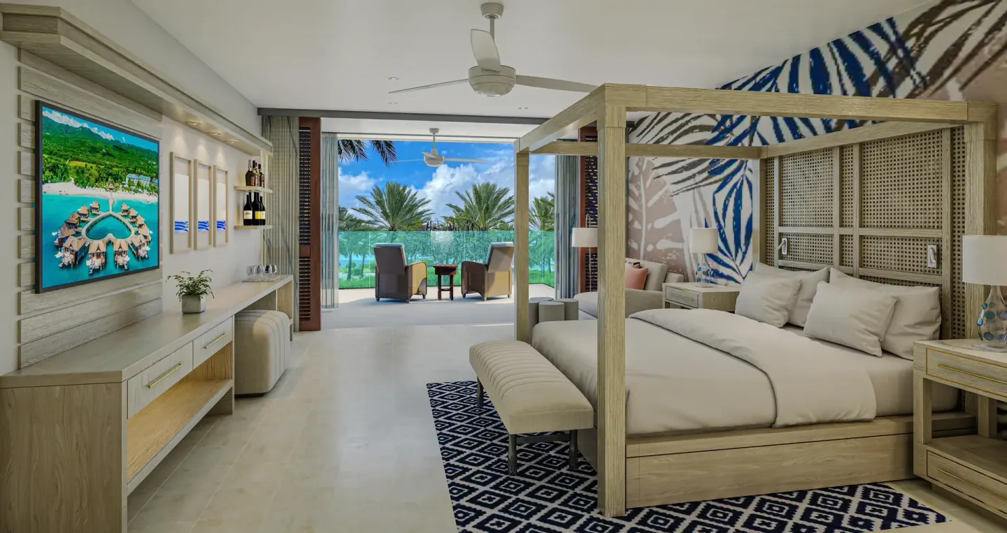 Carisia Luxury room with four-poster king bed and patio seating at Sandals Royal Curacao.