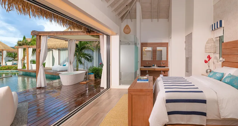 King bedroom opening to a patio soaking tub and pool at Sandals Royal Curacao.