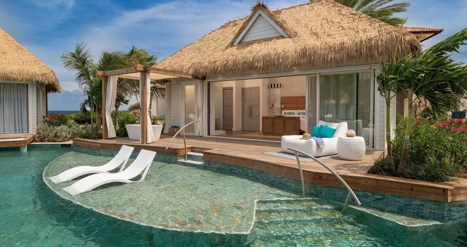 Poolside bungalow patio with loungers and open bedroom at Sandals Royal Curacao.