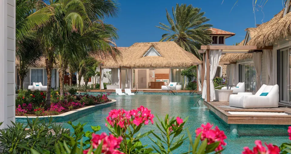 Thatched poolside bungalows and patios beside flowering gardens at Sandals Royal Curacao.