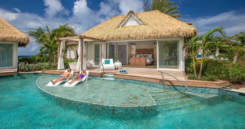 Guests lounging in the shallow pool beside a bungalow at Sandals Royal Curacao.