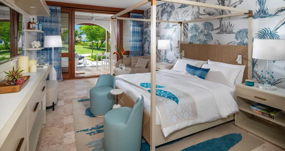 Melemele junior suite king bed at Sandals Royal Curacao with patio doors open to gardens.