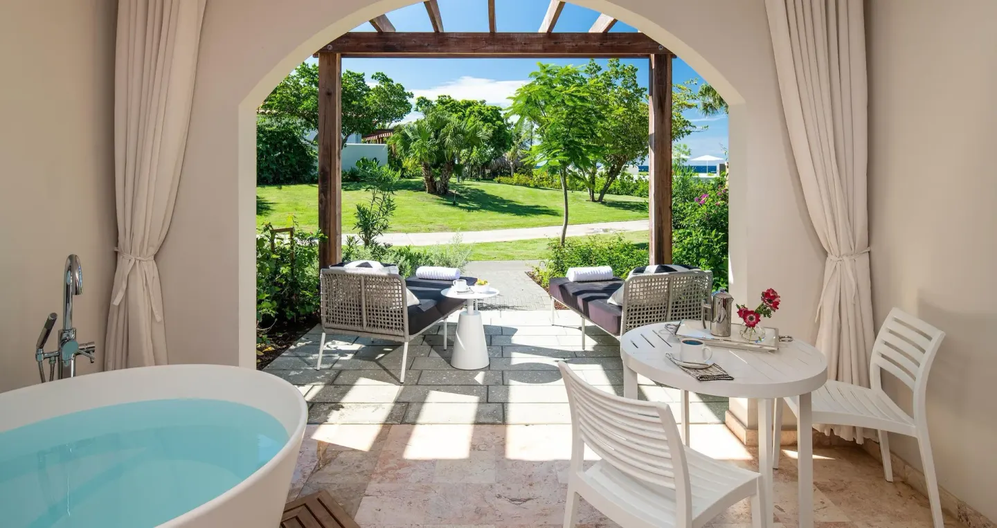 Walkout junior suite patio with soaking tub at Sandals Royal Curacao overlooking tropical gardens.