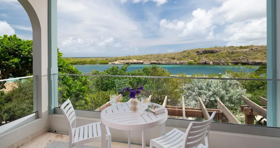 Sunchi Luxury Beachfront balcony with table and lagoon view at Sandals Royal Curacao.