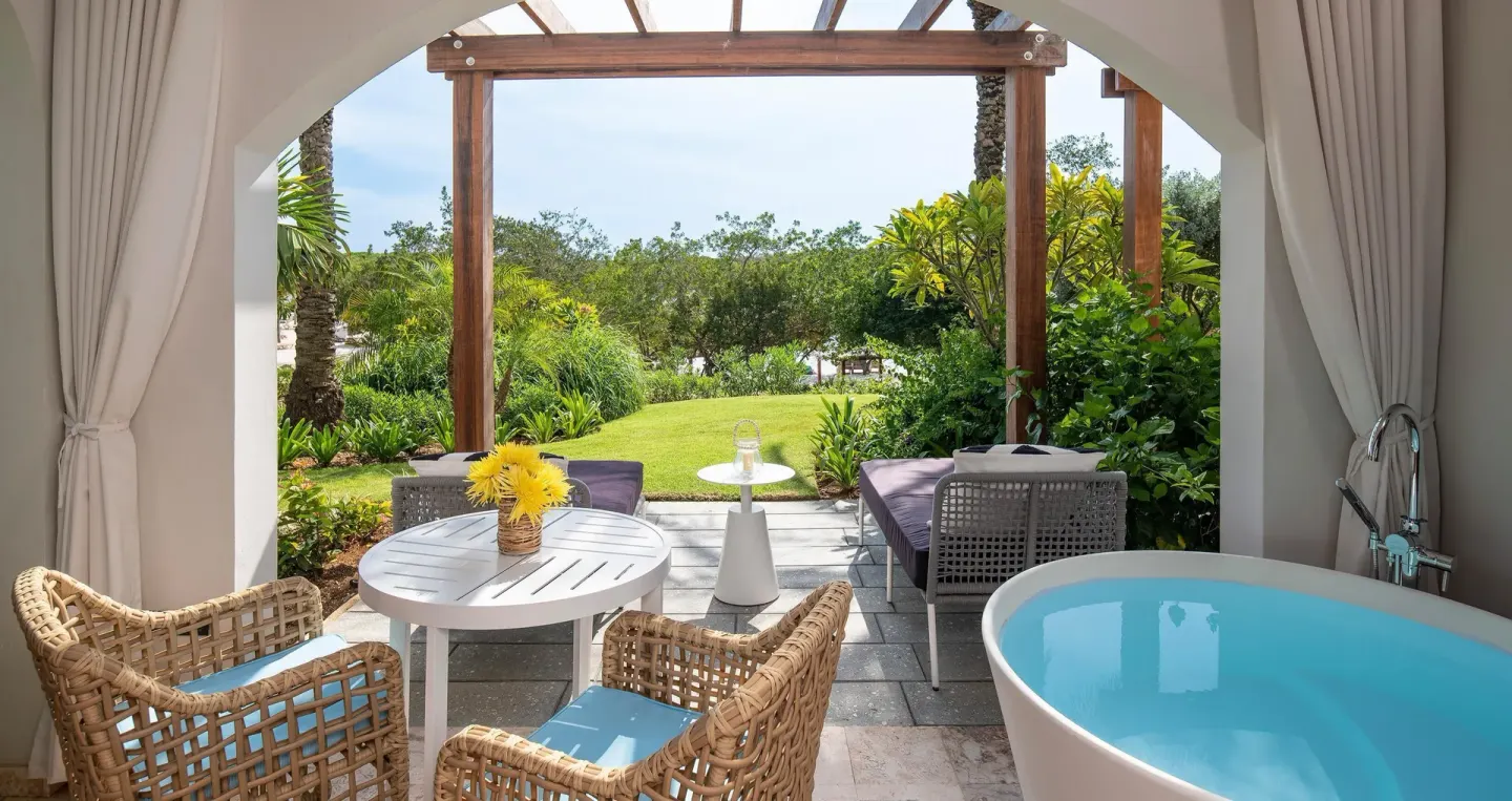 Patio soaking tub and garden seating for a beachfront room at Sandals Royal Curacao.