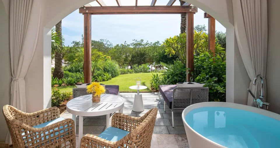Patio soaking tub and garden seating for a beachfront room at Sandals Royal Curacao.