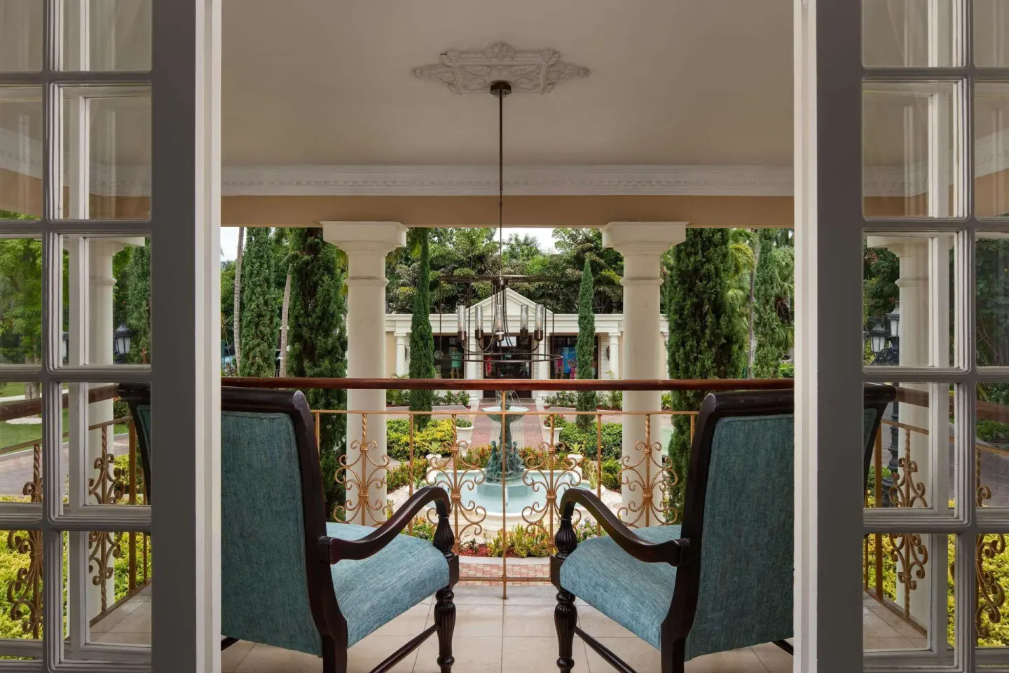 Balcony seating overlooking gardens and a fountain at Sandals Royal Plantation.