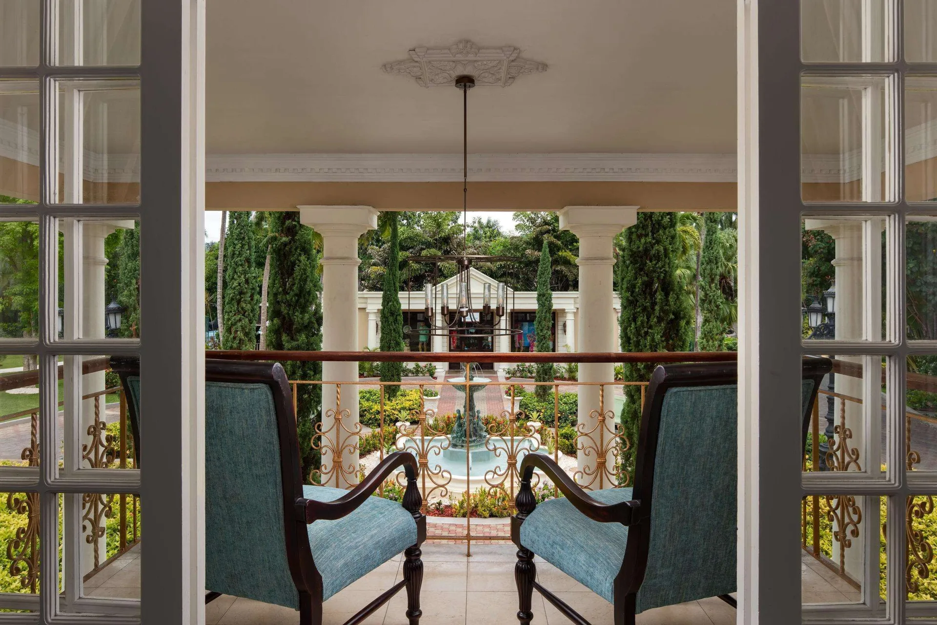 Balcony seating overlooking gardens and a fountain at Sandals Royal Plantation.