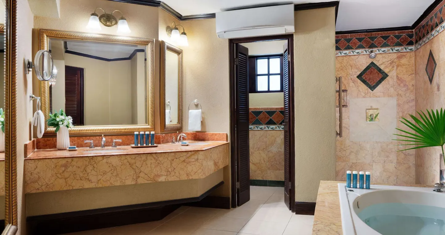Guest bathroom with vanity, tub, and tiled shower area at Sandals Royal Plantation.