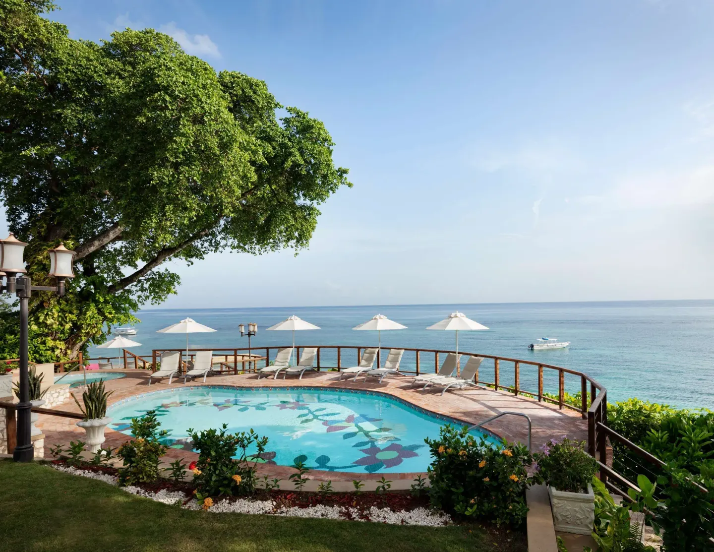 Seaside pool with loungers and umbrellas at Sandals Royal Plantation.