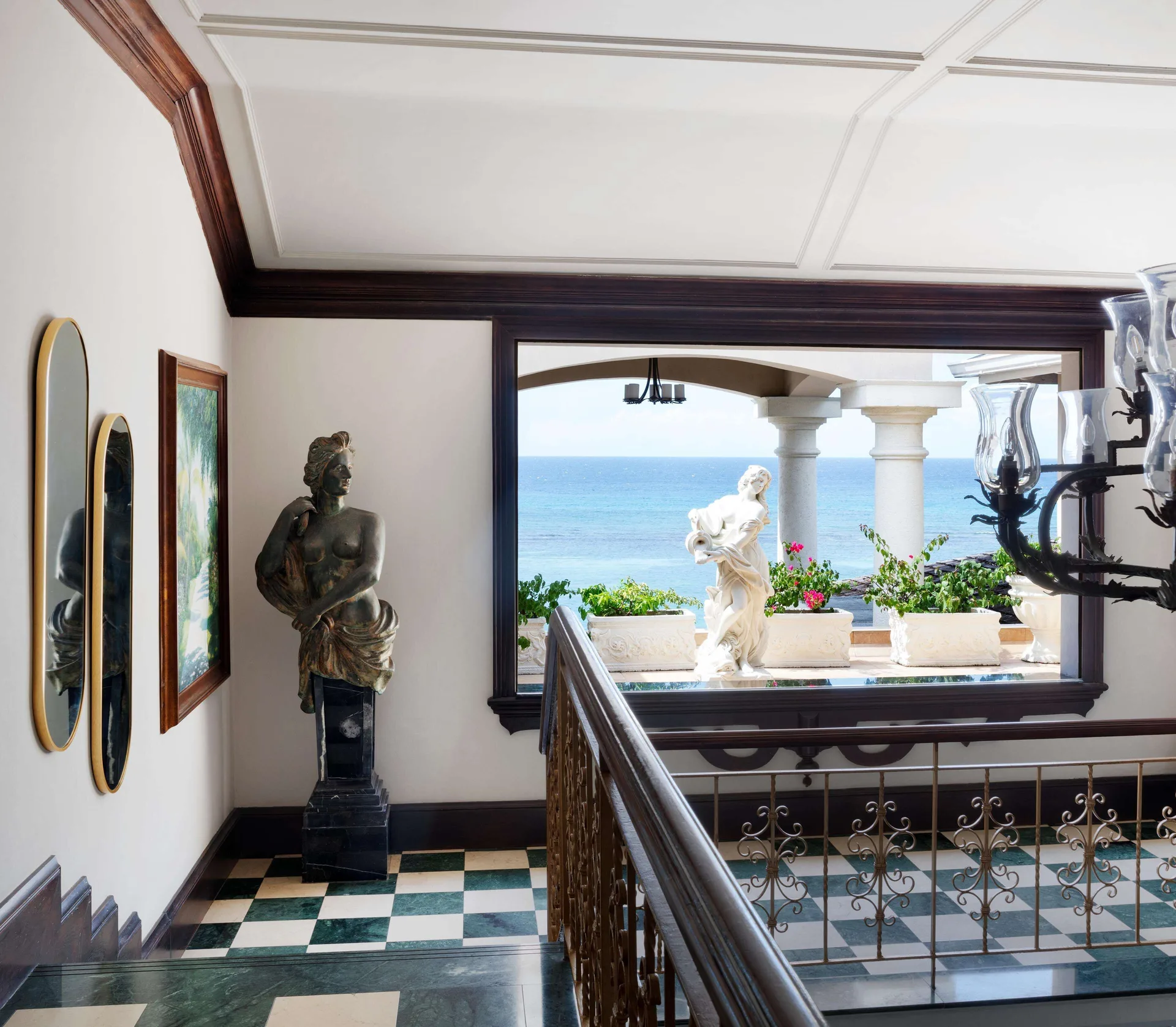 Stair landing with sculptures and ocean view at Sandals Royal Plantation.