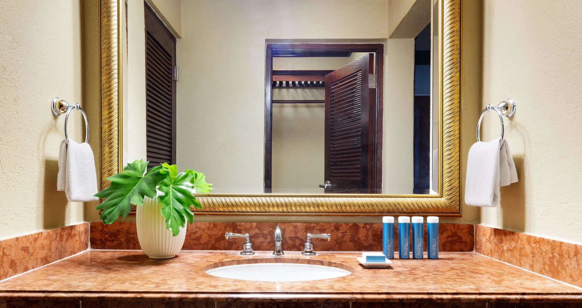 Bathroom vanity in a Royal Suite at Sandals Royal Plantation with mirror, sink, towels, and toiletries.