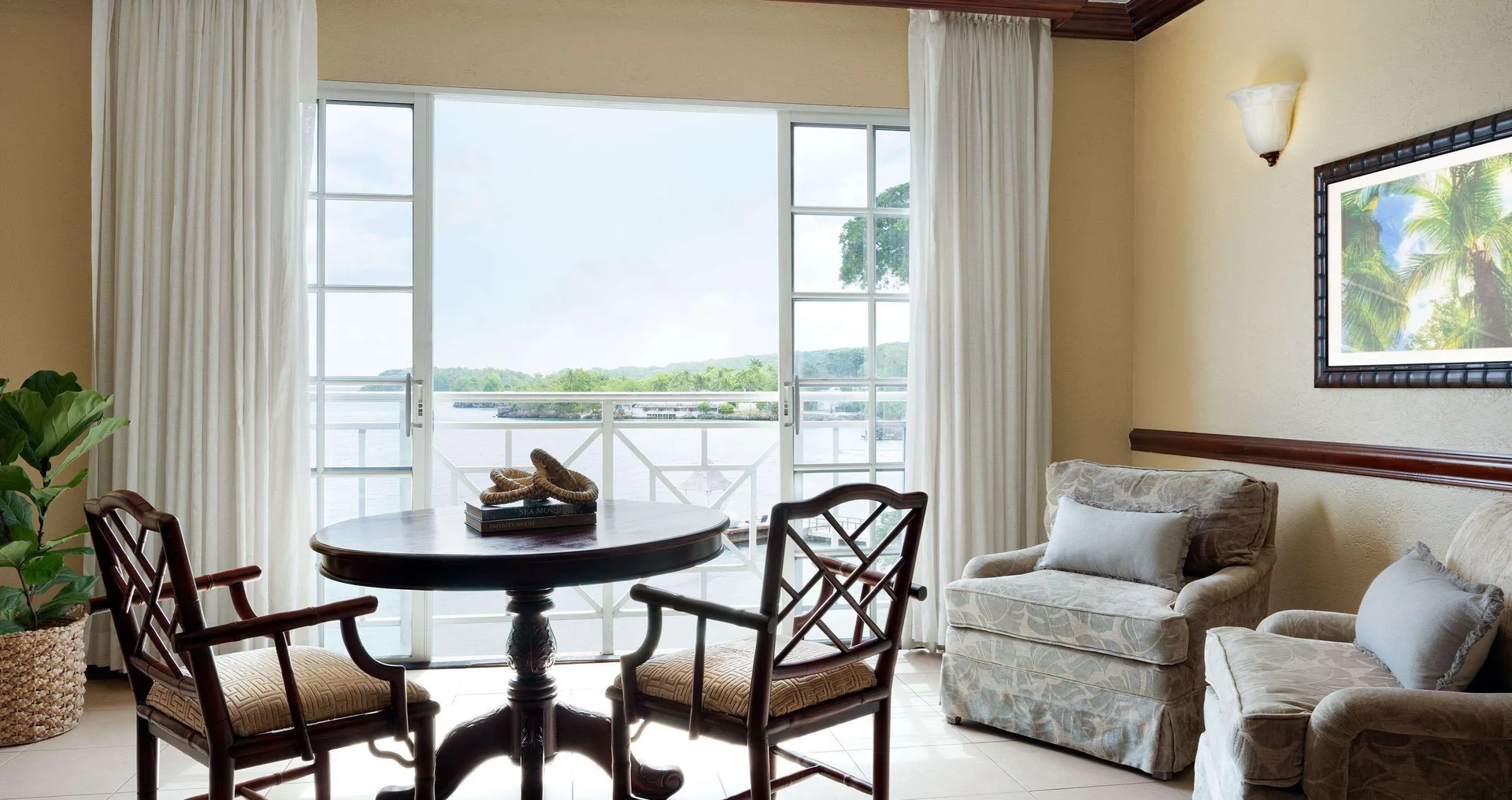 Ocean-view sitting area in a Royal Suite at Sandals Royal Plantation with chairs and balcony doors.