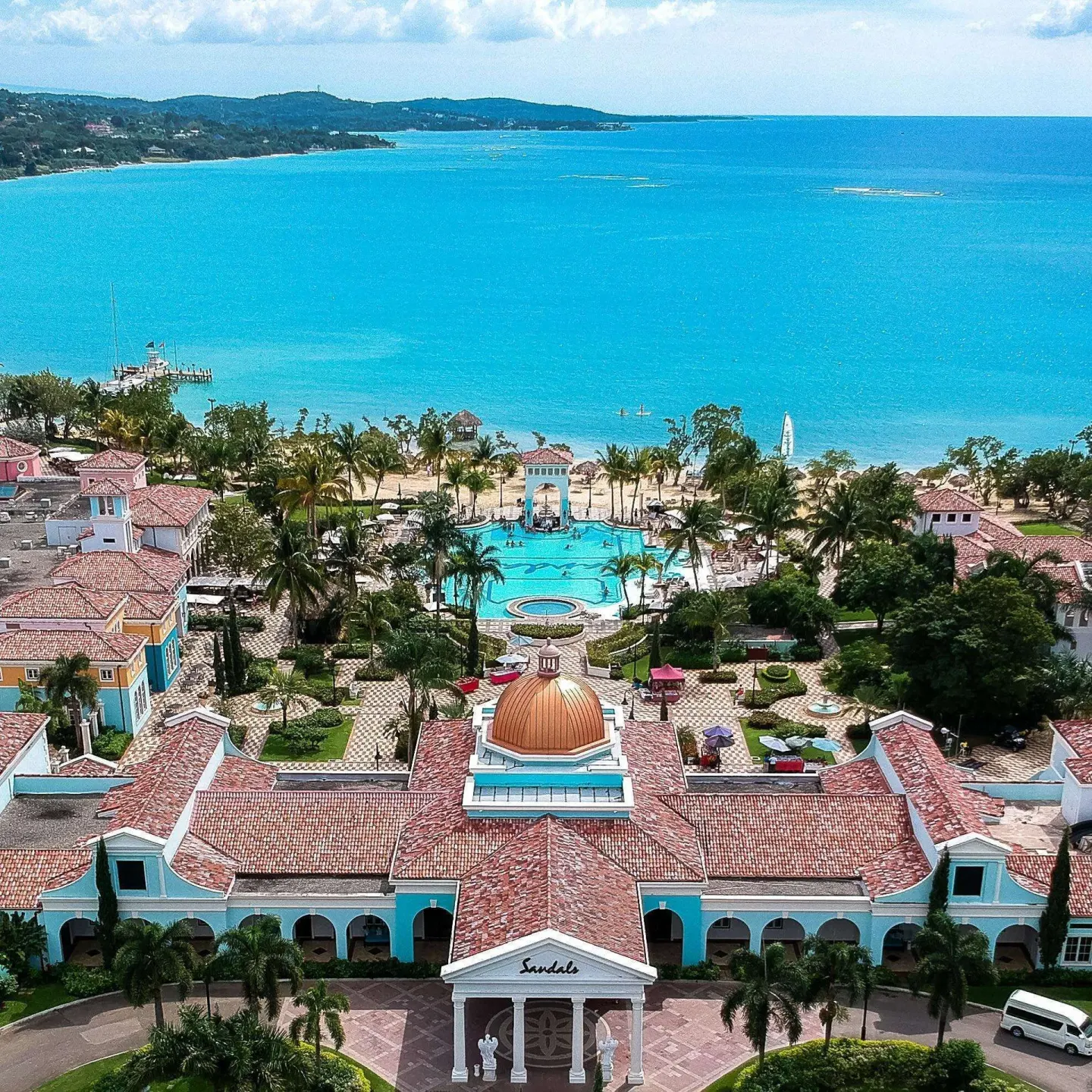 Aerial view over the domed building to the pool, beach, and turquoise sea at Sandals South Coast.