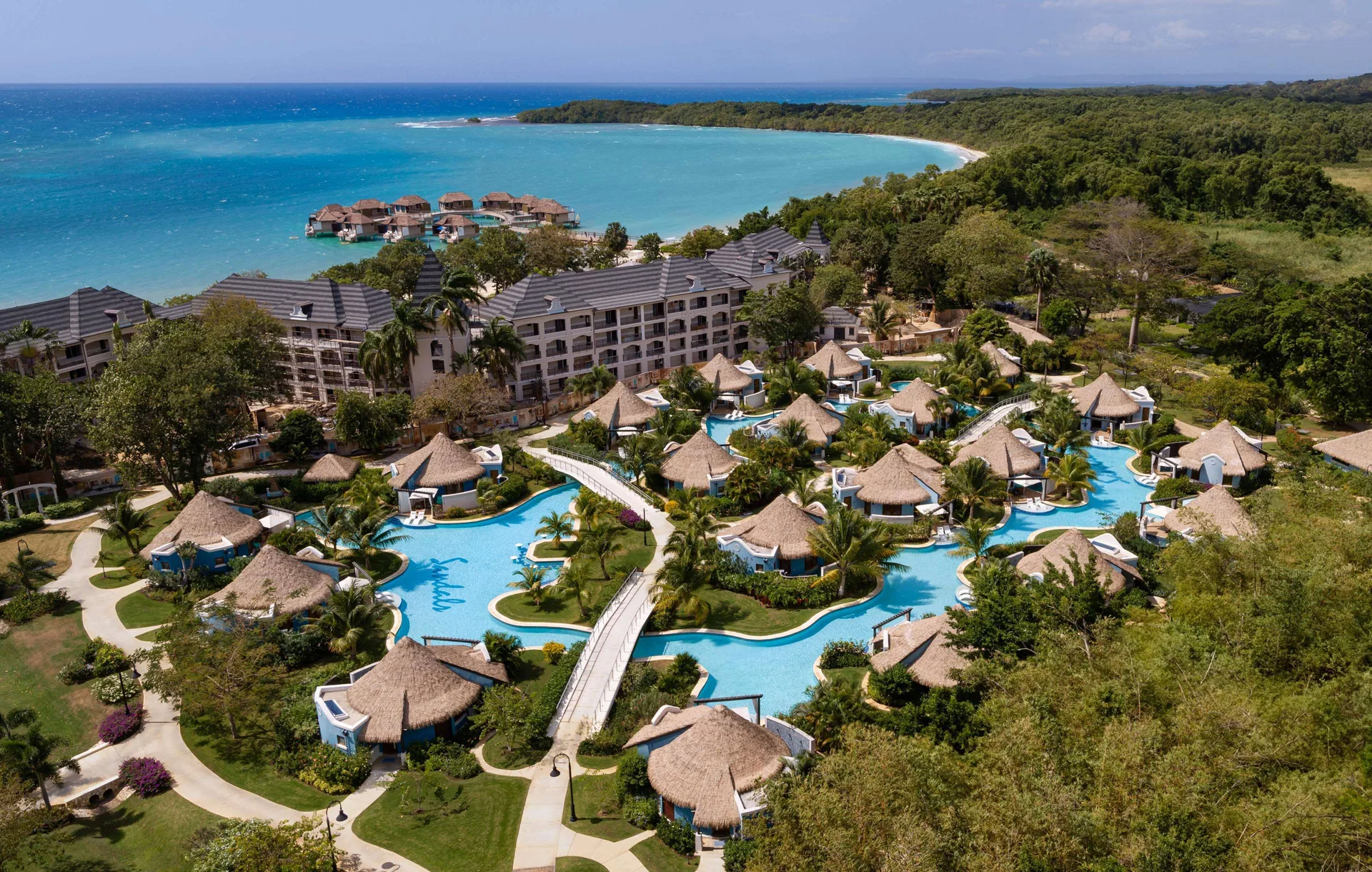 Aerial resort view with pools, beach, and overwater bungalows at Sandals South Coast.