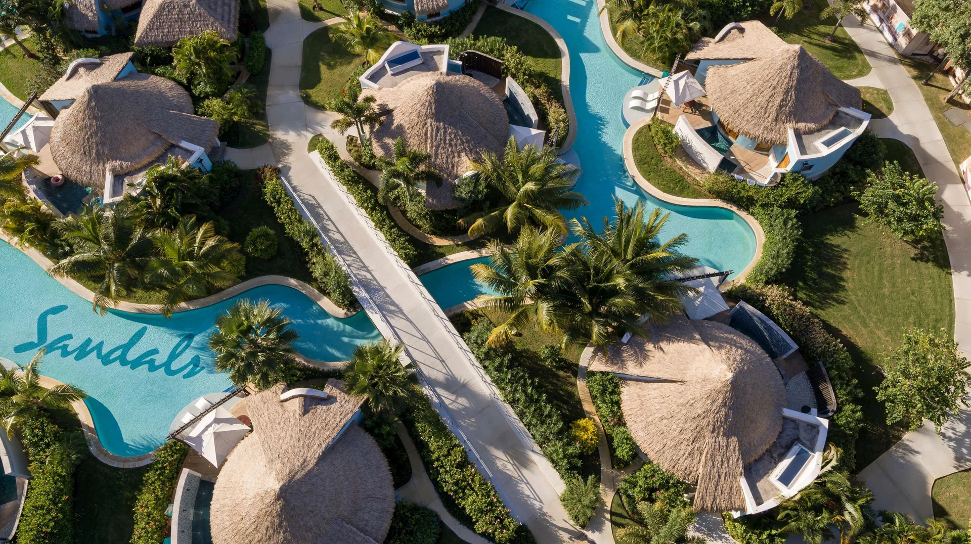 Aerial view of rondoval suites, pools, and palms at Sandals South Coast.