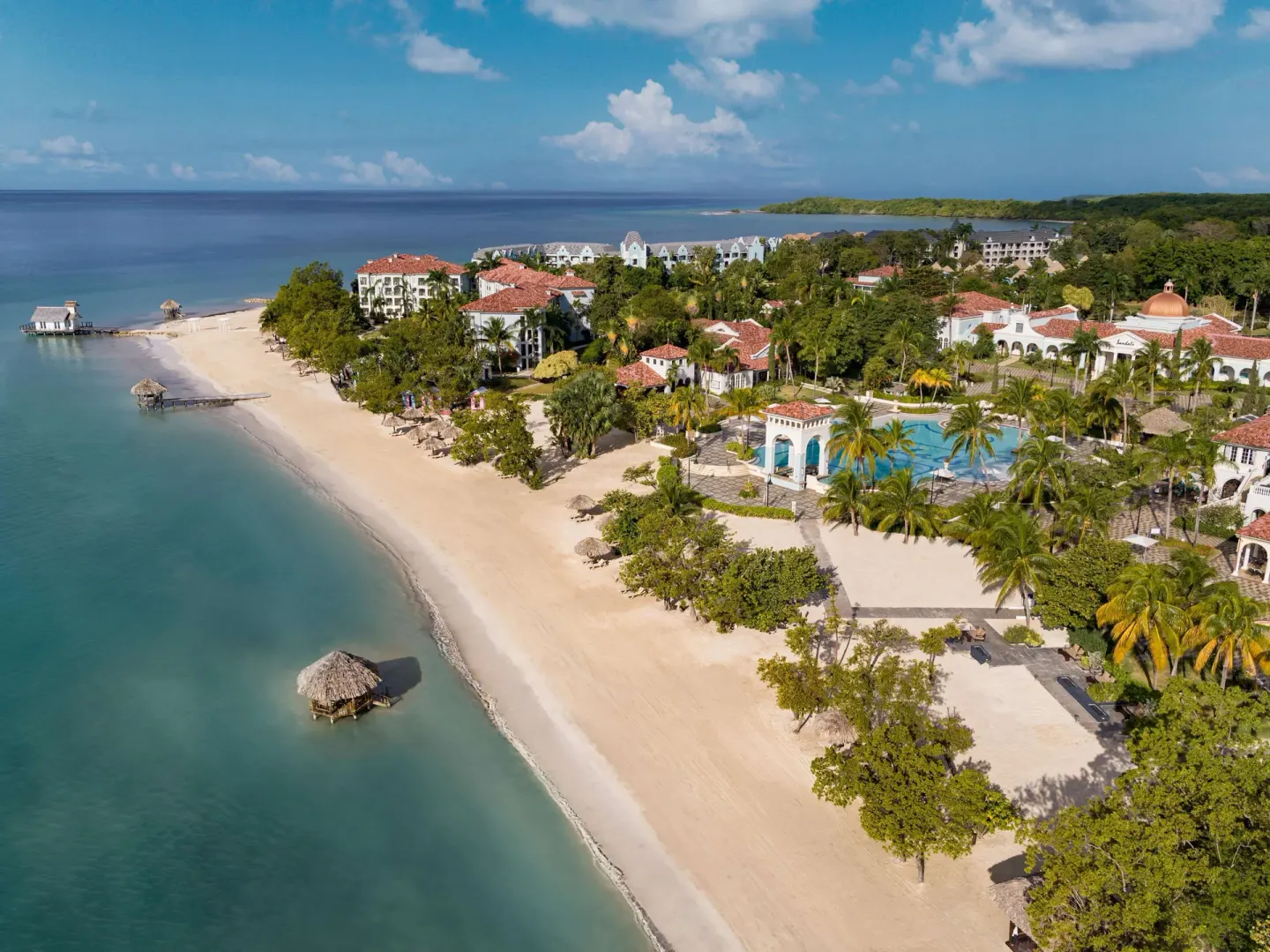 Beachfront buildings, pool area, and calm shoreline at Sandals South Coast.