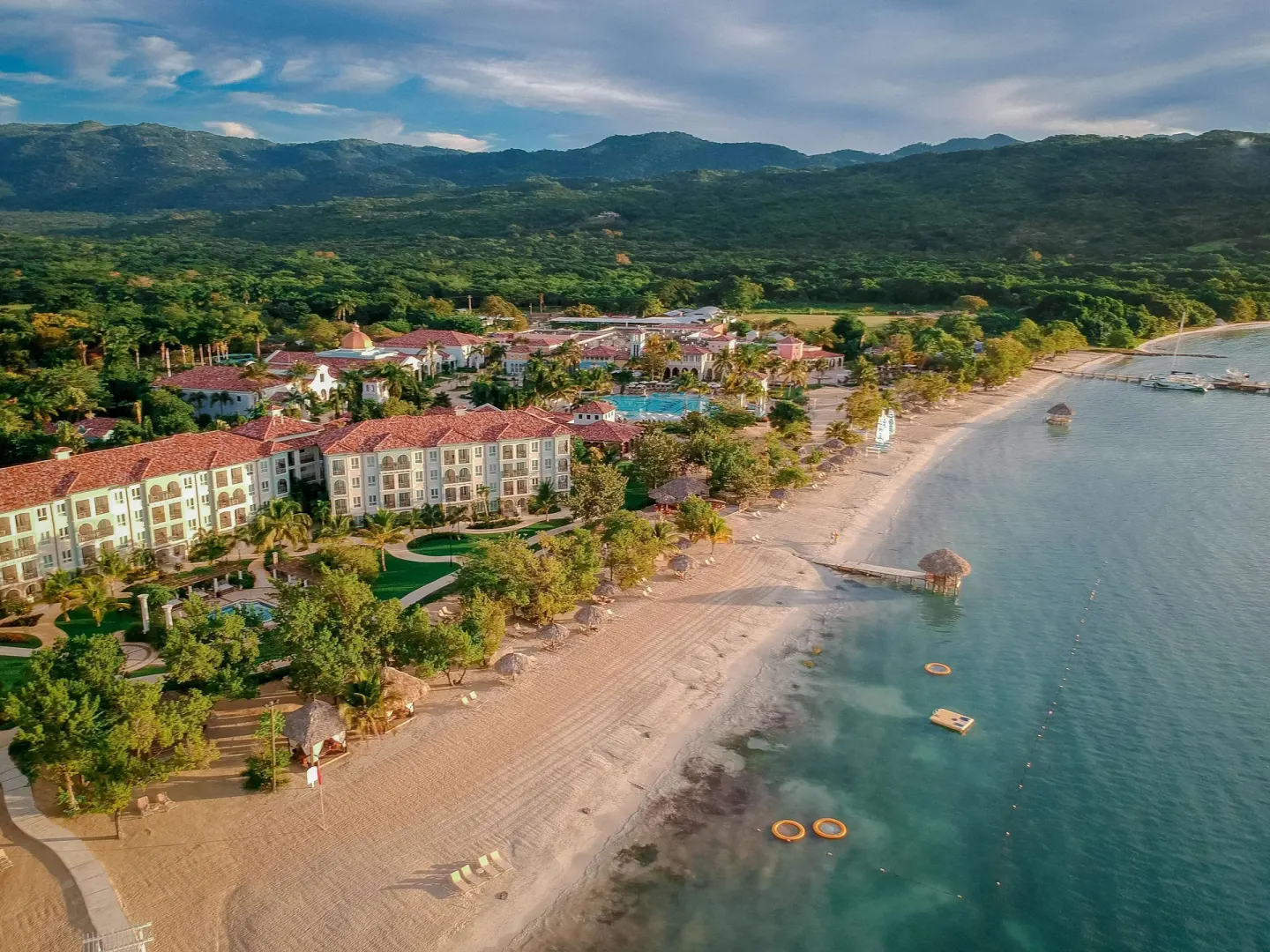 Aerial view of the beach, resort buildings, and mountains at Sandals South Coast.