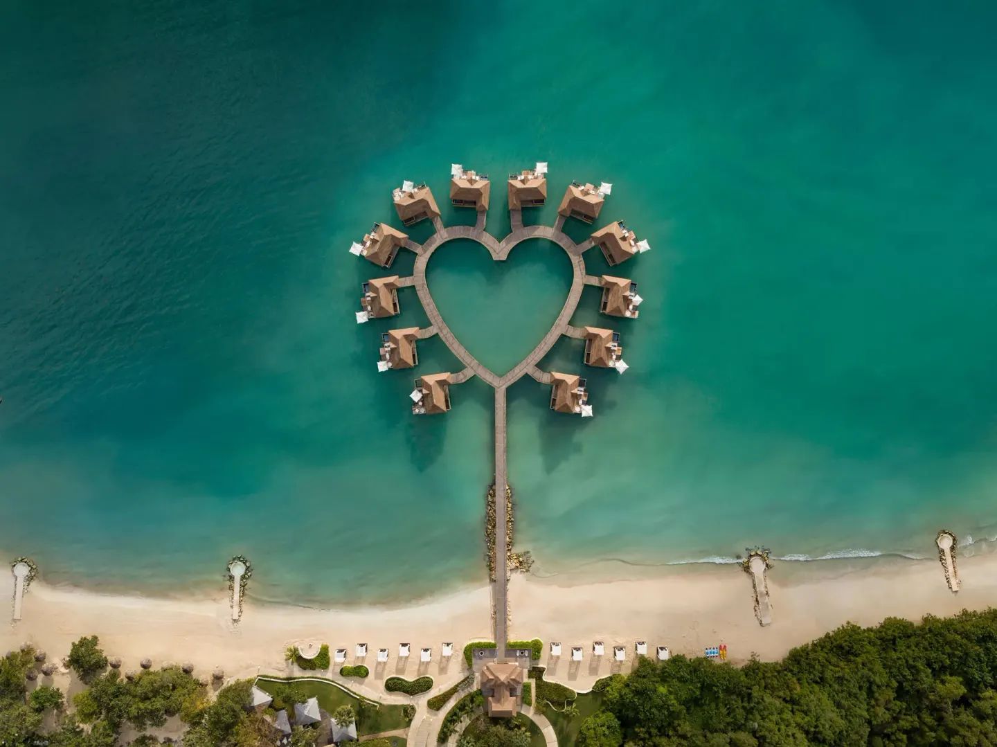 Heart-shaped overwater bungalows above turquoise sea at Sandals South Coast.