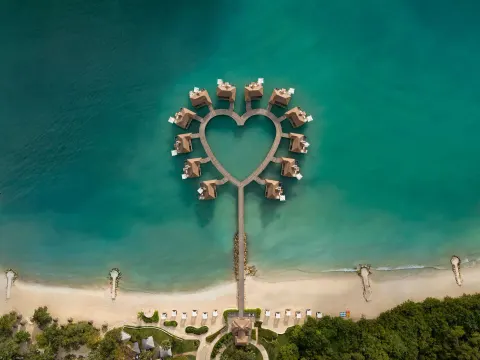 Heart-shaped overwater bungalows above turquoise sea at Sandals South Coast.