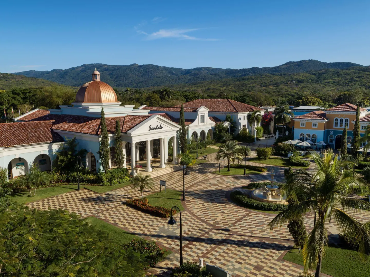 Main resort plaza and domed entrance at Sandals South Coast with mountains behind.