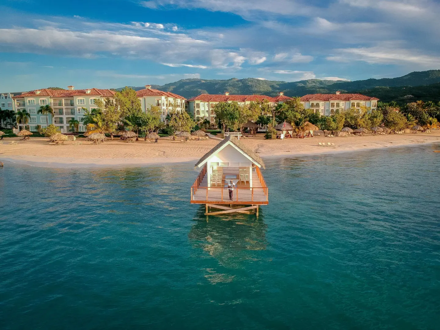 Aerial view of an overwater chapel, beach, and resort buildings at Sandals South Coast.