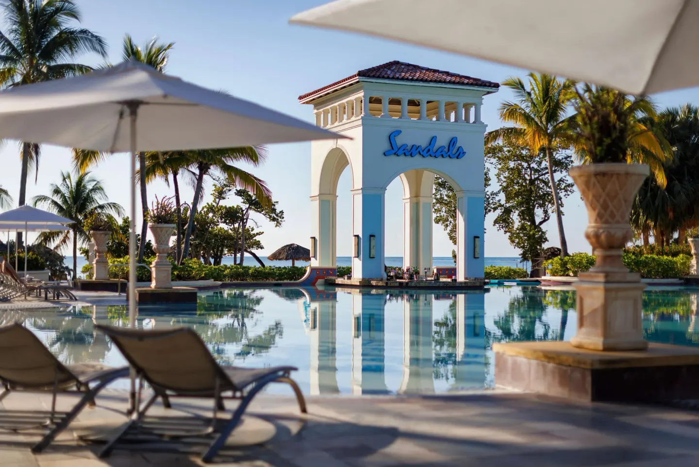 Pool loungers and umbrellas facing the Sandals arch at Sandals South Coast.