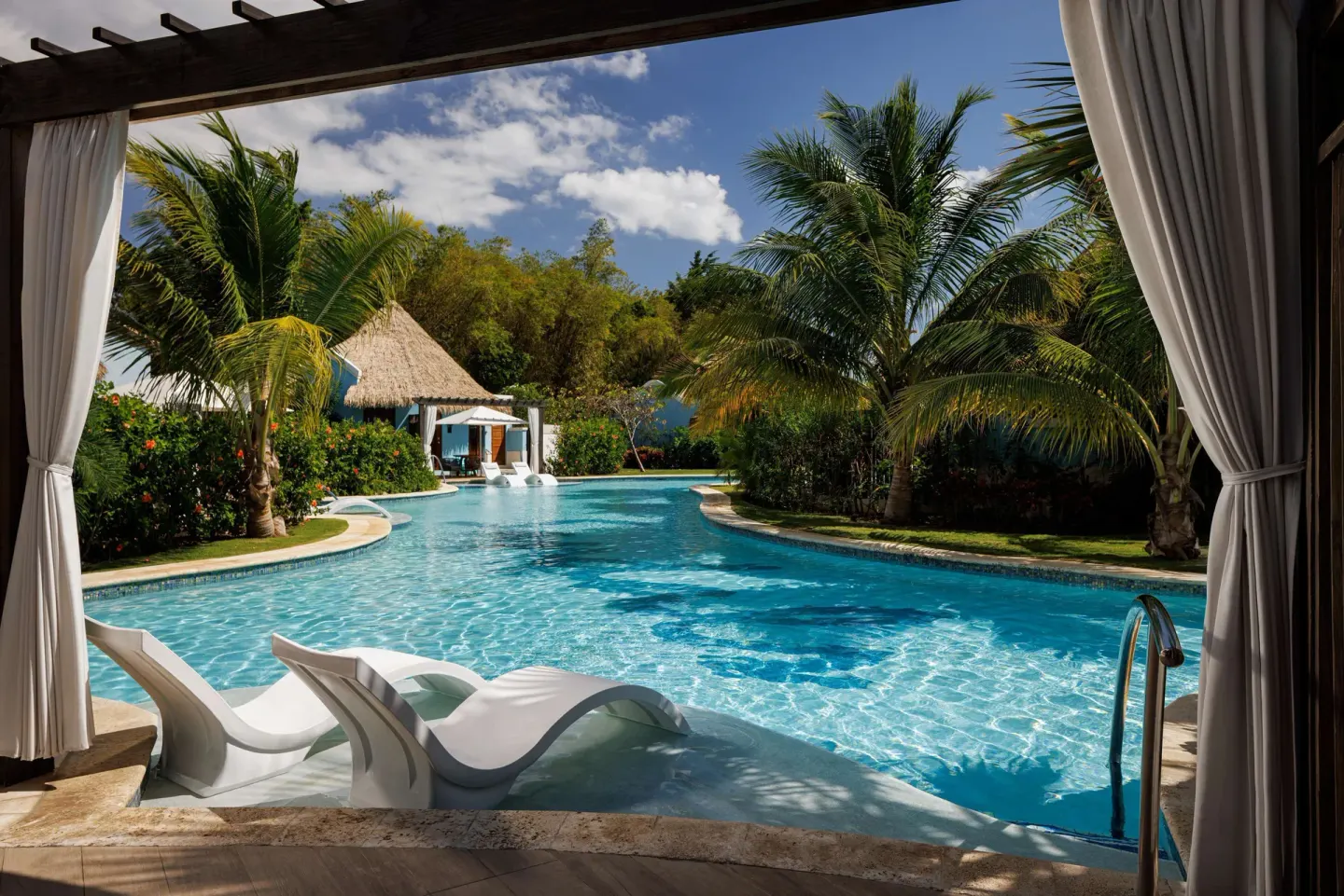 Swim-up pool area with in-water loungers and palms at Sandals South Coast.