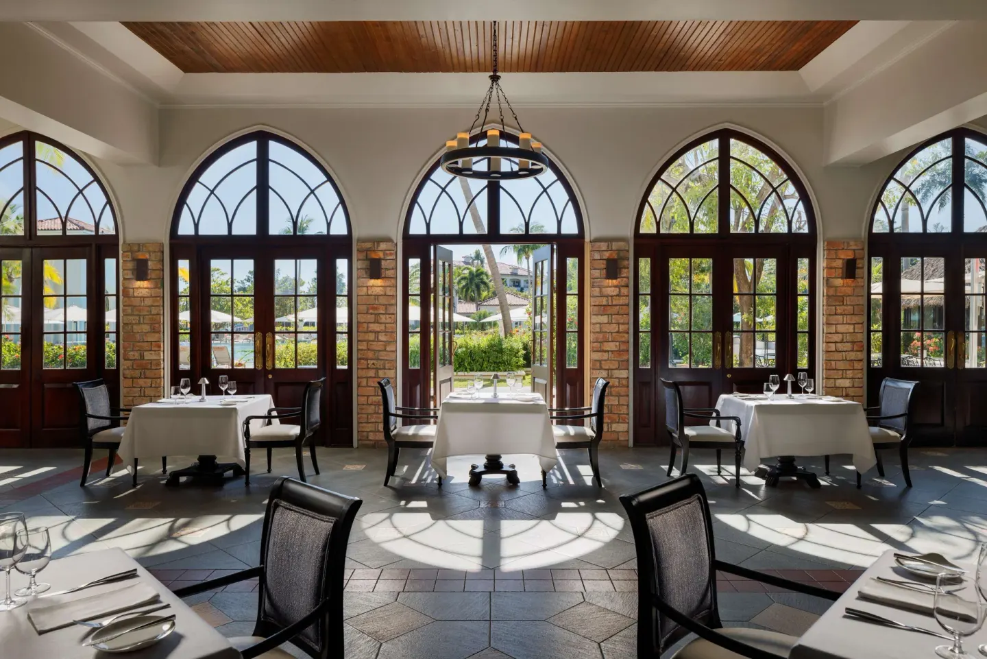 Elegant dining room with arched windows and set tables at Sandals South Coast.