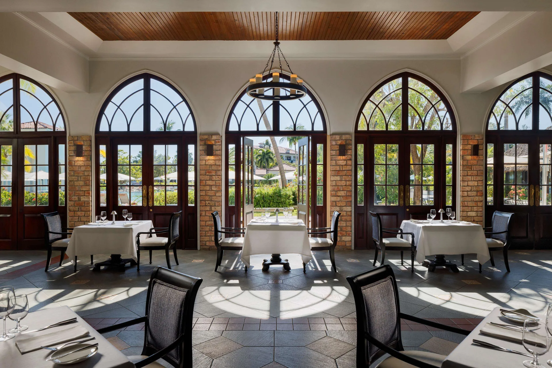 Elegant dining room with arched windows and set tables at Sandals South Coast.