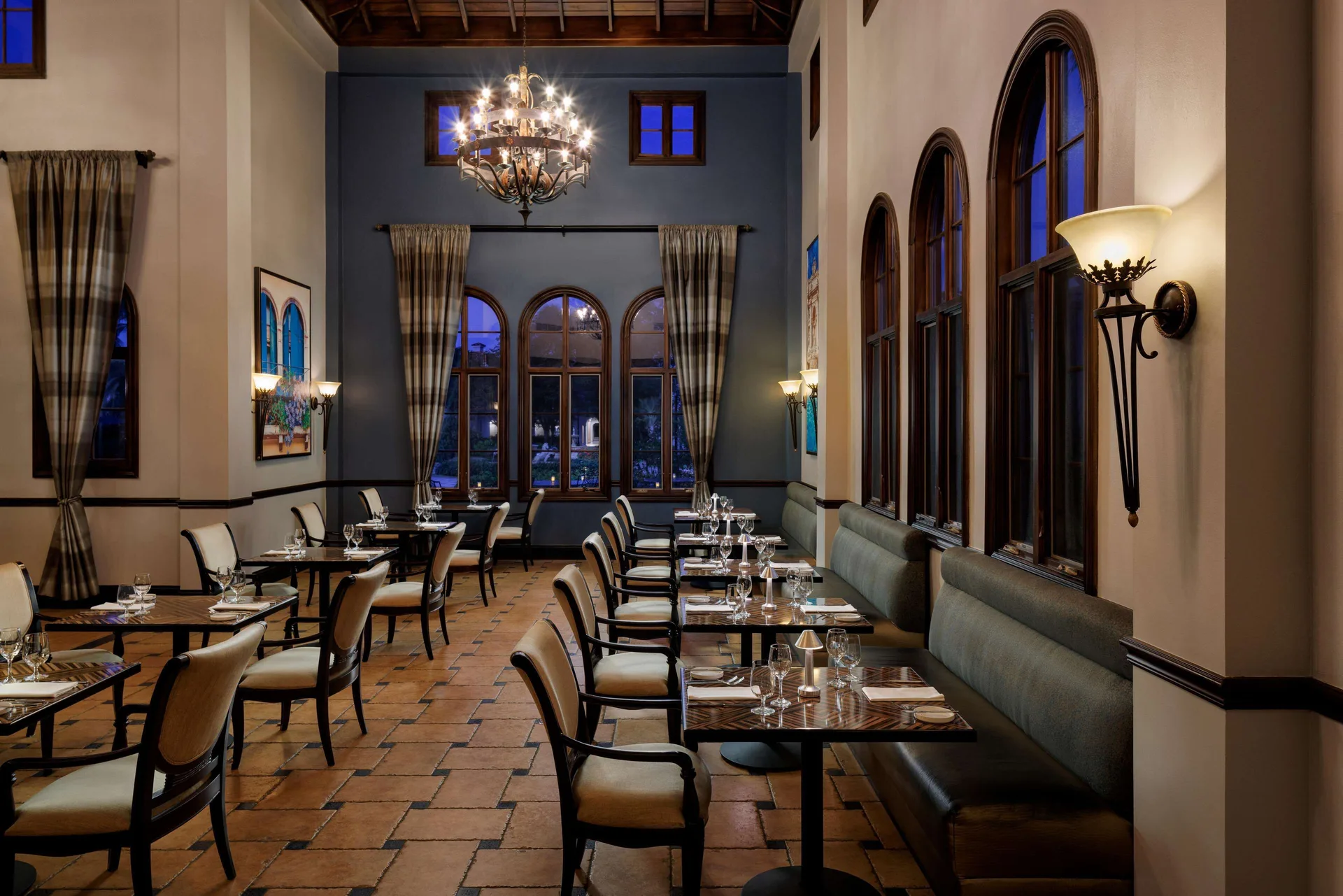 Evening dining room with high ceilings and arched windows at Sandals South Coast.