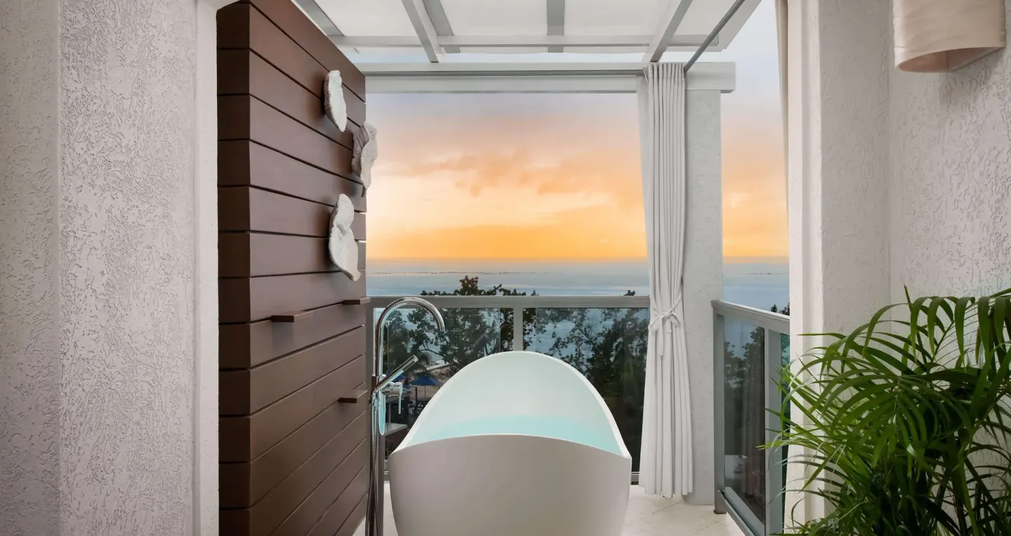 Balcony soaking tub with ocean sunset view in a Club Penthouse room at Sandals South Coast.