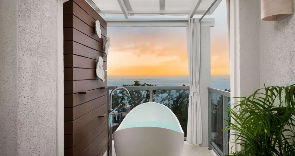Balcony soaking tub with ocean sunset view in a Club Penthouse room at Sandals South Coast.