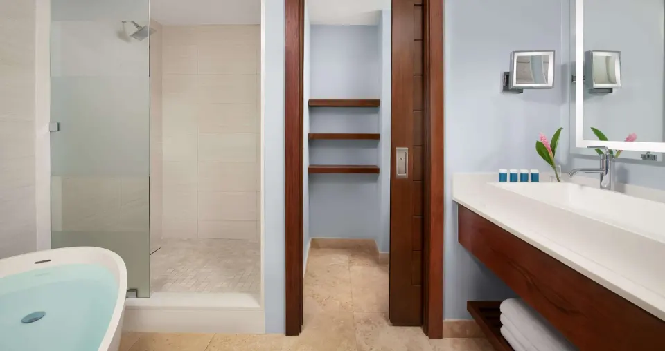 Bathroom vanity, soaking tub, and glass shower in a guest room at Sandals South Coast.