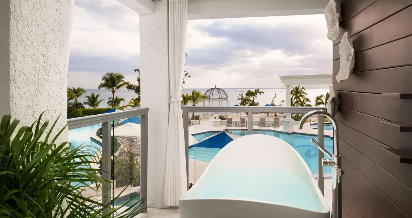 Beachfront balcony soaking tub with pool and ocean view at Sandals South Coast.