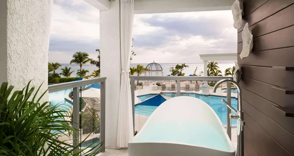 Beachfront balcony soaking tub with pool and ocean view at Sandals South Coast.