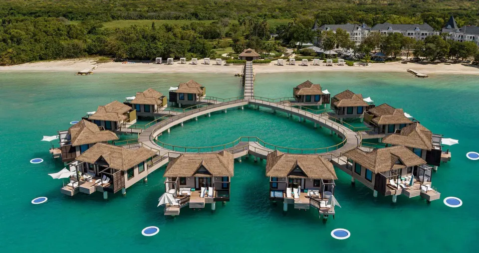 Aerial view of overwater villas connected to the beach at Sandals South Coast.