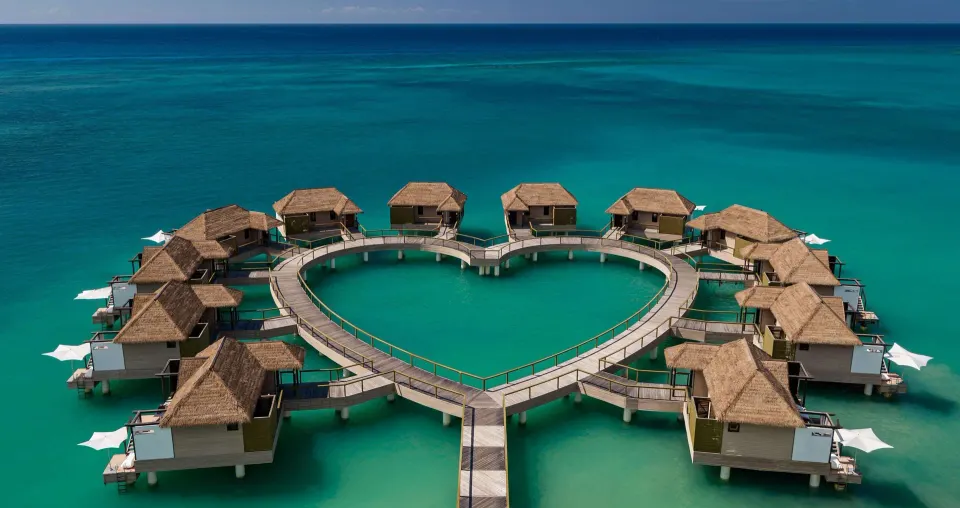 Heart-shaped overwater villa walkway in turquoise sea at Sandals South Coast.