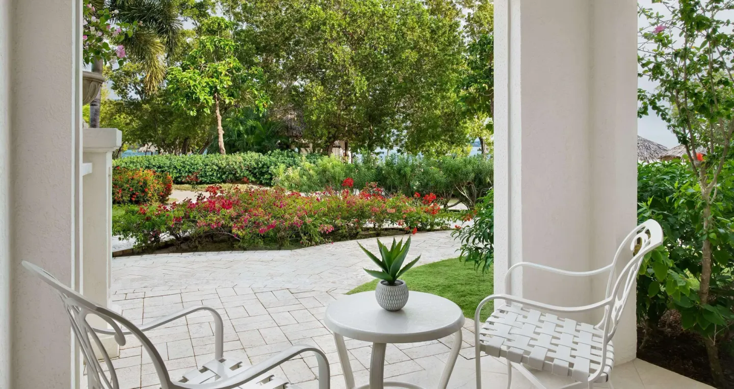 Walkout patio seating outside a honeymoon room at Sandals South Coast with garden landscaping.