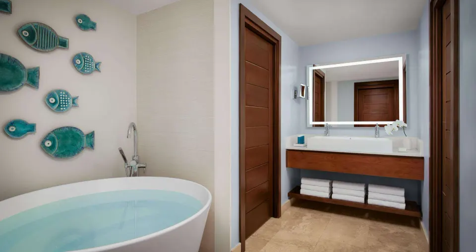 Bathroom with soaking tub, vanity, and fish wall art at Sandals South Coast.