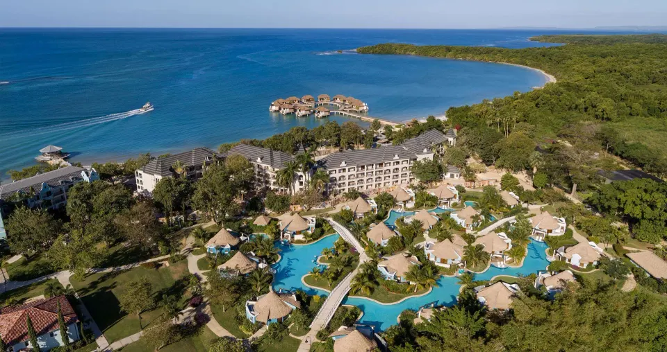 Aerial view of rondoval villas, pools, beach, and overwater rooms at Sandals South Coast.