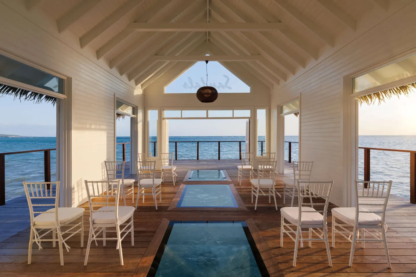Interior of an overwater chapel with white chairs and glass floor panels at Sandals South Coast.
